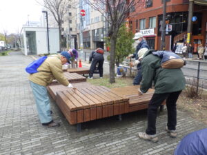 4月19日に狸二条広場の縁台の塗装をするお助け隊のメンバー