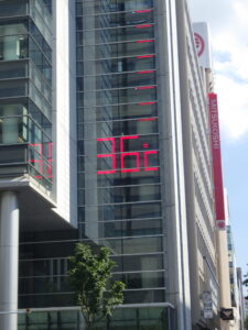 8月23日水曜日のお昼過ぎの駅前通りのビルの温度計が36度を指す様子