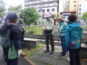 10月3日の植物ボランティアで指導の笠先生からハギの説明を受ける様子