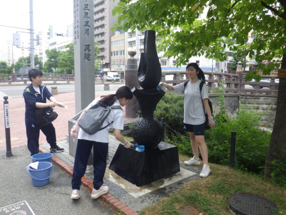 モニュメントの清掃をする高校生ボランティアとお助け隊