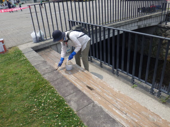 7月3日に狸二条広場の北側のベンチの塗装作業をするお助け隊