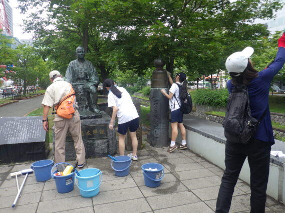 モニュメントの清掃をする高校生ボランティアとお助け隊