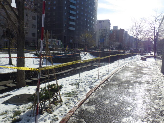 狸二授広場南側の芝生斜面と川の飛び石の立ち入り禁止の様子