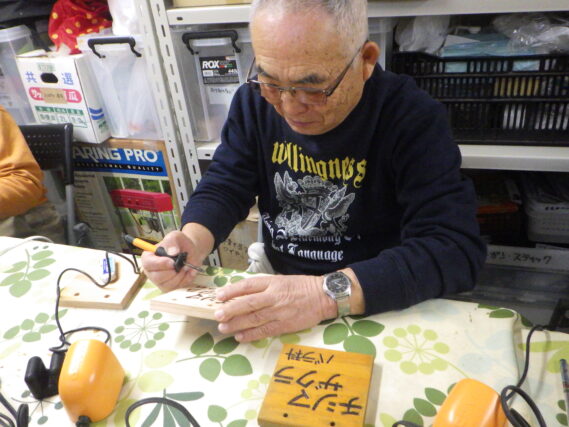 バーニングペンで樹名板の作成をする植物ボランティア