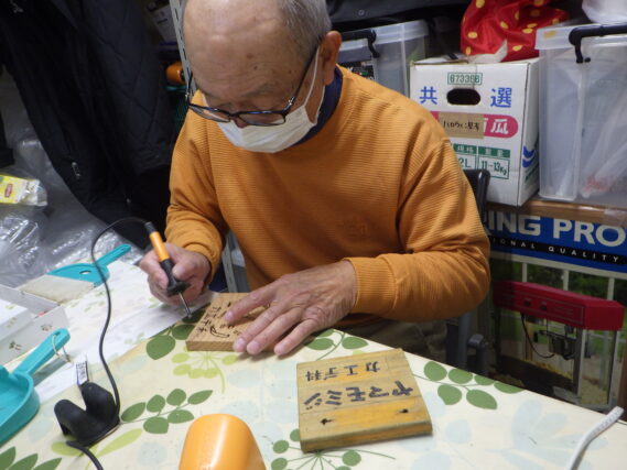 バーニングペンで樹名板の作成をする植物ボランティア