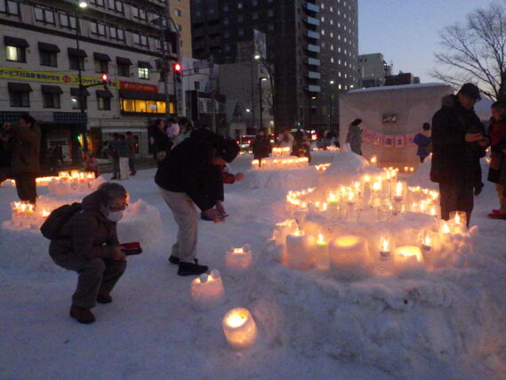 点灯されたスノーキャンドルと見に来た人たちの様子