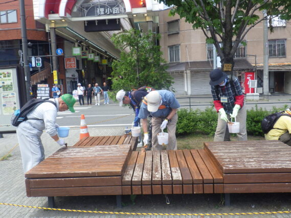 狸二条広場の縁台を塗装するお助け隊