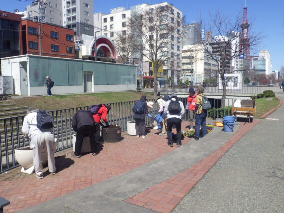 狸二条広場のコンテナに花を植え込む花くらぶ