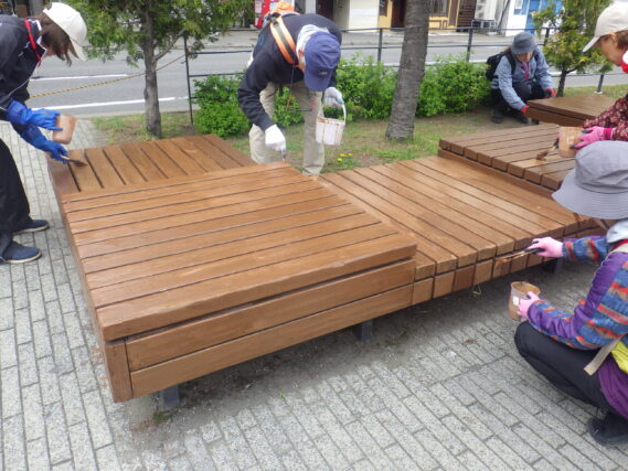 狸二条広場のベンチの塗装をするお助け隊