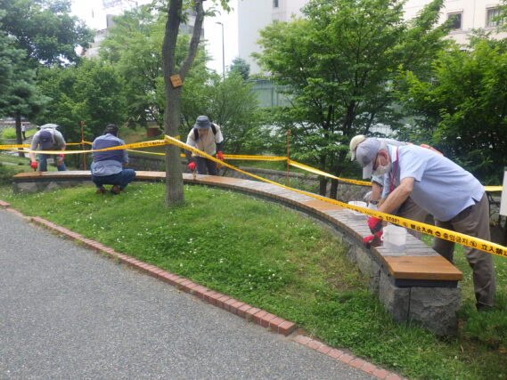 石積み円形ベンチの塗装をするお助け隊