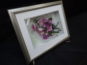 奥行きのある額にバラが花束のように飾られている作品