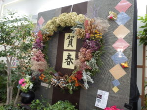 大リースの中央に「賀春」の色紙、周辺にも和柄の飾り付けがついている