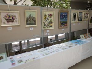 壁に飾られた花額作品とクリアファイルやしおり等の小物作品が並ぶ