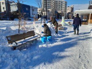 園路脇で数人のスタッフが雪像を作っている