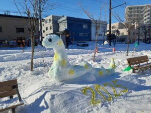 雪で作ったヘビ。立ち上がっていて、本体が緑地に黄色の水玉模様が入っている。