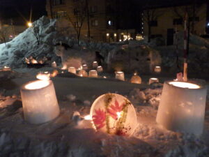 あたりが暗くなっていて、雪の上に灯りの灯ったスノーキャンドルやアイスボードが並んでいる