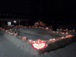 手前の雪の上に赤いこぶし大の氷でハート形を作り内側にろうそくをそもしている。その左右や奥側にもアイスボードやスノーキャンドルなどが並んでいる